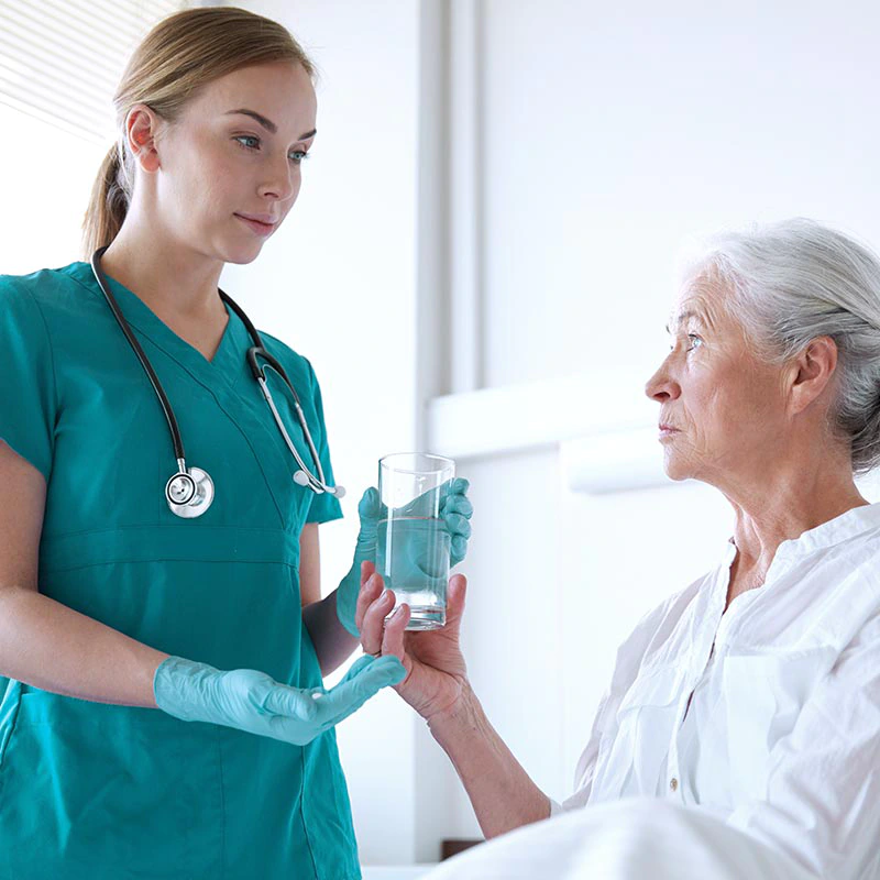 Hygienebeauftragter in der Pflege / im Gesundheitswesen (IHK) Eine Pflegerin reicht einer Patientin Tabletten und ein Glas Wasser